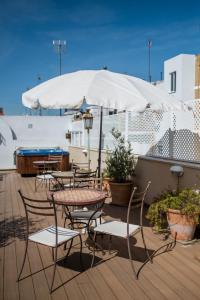 un patio con mesas, sillas y una sombrilla en Alcoba del Rey de Sevilla, en Sevilla