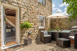 a patio with a table and an umbrella at White Rose Cottage in Constable Burton
