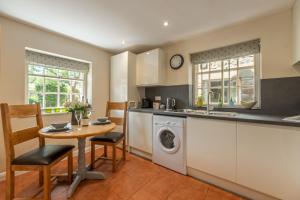 a kitchen with a table and a washer and dryer at White Rose Cottage in Constable Burton