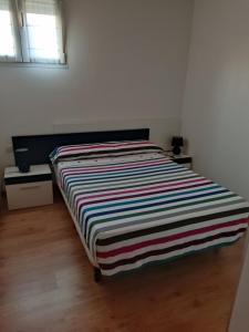 a bed in a room with a striped blanket on it at La ventana de la catedral in Burgos