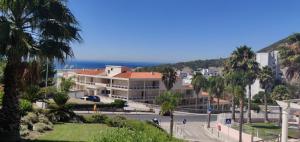a view of a street with palm trees and the ocean at Appartement Quinta de Palames Sesimbra in Sesimbra