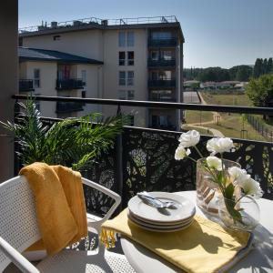 uma mesa com pratos e um vaso de flores numa varanda em Résidence service senior DOMITYS LES ALEXIS em Montélimar