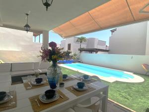 een zwembad met een tafel en een vaas met bloemen bij Aquavilla in Costa Teguise