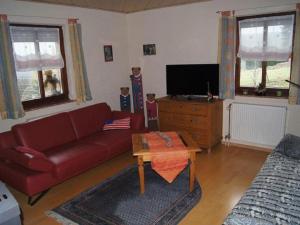 a living room with a red couch and a tv at Ferienwohnung Haus am Berg in Innernzell