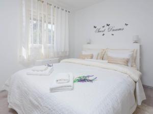 a white bedroom with a large white bed with towels on it at Apartment Lana ST in Supetar