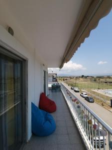 un balcón con 2 sillas rojas y azules en un edificio en Elef Apartment, en Paralia Dionisiou