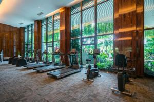 a gym with a row of tread machines and large windows at Forest City Marina Hotel in Nusajaya
