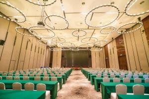 a row of chairs in a hall with green tables at Forest City Marina Hotel in Nusajaya