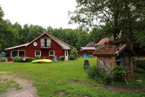 uma casa vermelha com um barco amarelo no quintal em namelis nr 2 Adelės sodyba em Muižė