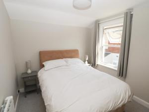 a white bed in a room with a window at The Bothy in Lytham St Annes