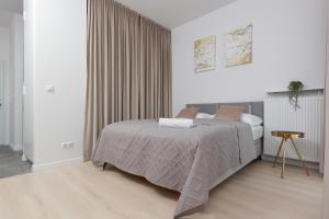 a white bedroom with a bed and a table at Golden Apartments Ursynów by Renters in Warsaw
