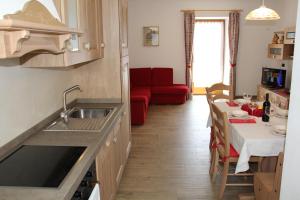 una cucina con lavandino e tavolo con divano rosso di Appartamenti Dany ad Arabba