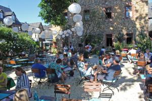 un groupe de personnes assises sous les chaises devant un bâtiment dans l'établissement Weinhotel Koegler, à Eltville