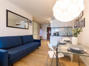 a living room with a blue couch and a glass table at VacationClub - Sand Hotel Apartment 201 in Kołobrzeg