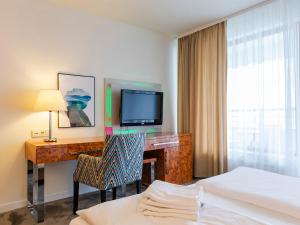 um quarto de hotel com uma secretária, uma televisão e uma cama em VacationClub - Sand Hotel Apartment 201 em Kolobrzeg