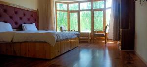 a bedroom with a bed and a large window at Zee Guest House in Leh