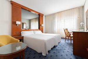 Una habitación de hotel con una gran cama blanca y un escritorio. en Exe Coruña, en A Coruña 57 fotos más