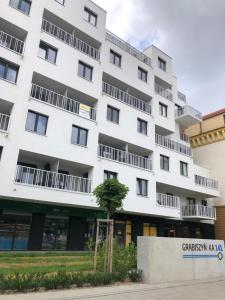 a white building with a tree in front of it at Apartament De Lux Apart 45 Grabiszyńska in Wrocław