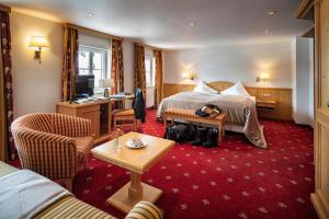 ein Hotelzimmer mit einem Bett und einem TV in der Unterkunft Hotel Tannbergerhof im Zentrum von Lech in Lech am Arlberg