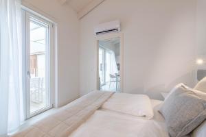 a white bedroom with a bed and a window at Pareus Beach Resort in Caorle