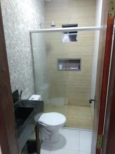 a bathroom with a toilet and a glass shower at Dunas Residence in Santo Amaro