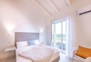 a white bedroom with a bed and a large window at Pareus Beach Resort in Caorle
