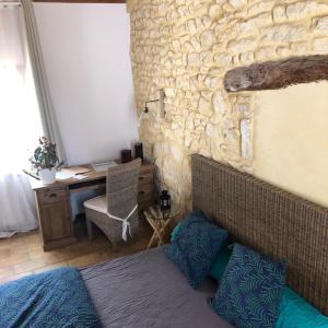 - une chambre dotée d'un mur en pierre avec un lit et un bureau dans l'établissement Nico Zen Home, à Vendargues