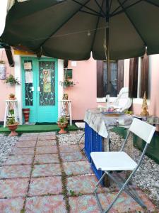 an umbrella and a chair in front of a house at Art B&B La Casa del Pittore in Revine Lago