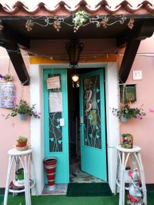 une maison rose avec une porte bleue et deux tabourets dans l'établissement Art B&B La Casa del Pittore, à Revine Lago