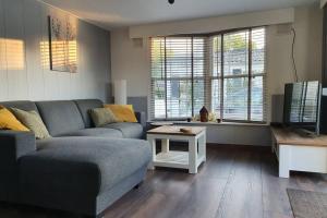 una sala de estar con un sofá y una mesa en Vazonics Valkenbosch 76, en Oisterwijk