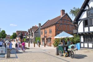 Ein Mann sitzt auf einem Imbisswagen auf einer Straße in der Unterkunft The Teapot Cottage in Town Centre FREE Parking in Stratford-upon-Avon