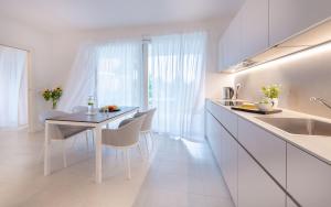 a white kitchen with a dining table and chairs at Pareus Beach Resort in Caorle