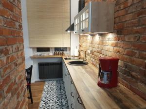 a kitchen with a counter and a brick wall at H&T Apartament Przy Starym Ratuszu in Gdańsk