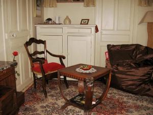 een woonkamer met 2 stoelen en een tafel en een bank bij Sylvie BARON - Composition Française - Chambres d'hôtes in Romans-sur-Isère