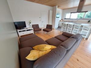 a living room with a brown couch and a kitchen at vakantiewoning met permanent verwarmd zwembad en sauna in Koekelare