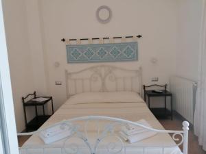 ein Schlafzimmer mit einem weißen Bett und zwei Nachttischen in der Unterkunft Giardini Malaspina in Bosa