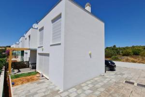 a white house with a garage at Mansion Duje in Brodarica