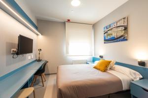 1 dormitorio con 1 cama y escritorio con TV en Residencia Universitaria Resa San Mamés, en Bilbao