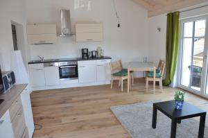 una cocina con armarios blancos y una mesa en una habitación en Ferienwohnungen Rimsting am Chiemsee, en Rimsting