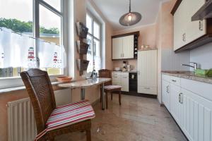 Una cocina con mesa y sillas y ventanas. en Villa zur See - FeWo 10, en Heringsdorf
