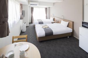 a hotel room with two beds and a table at Coruscant Hotel NagasakiekiⅢ in Nagasaki