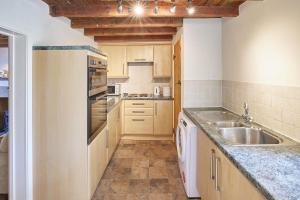 una cocina con armarios de madera y fregadero en Host & Stay - Grange Cottage en Osmotherley