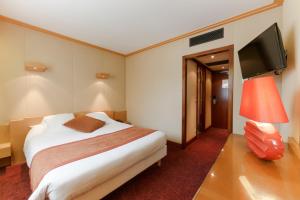 a hotel room with a bed and a flat screen tv at Hôtel du Béryl, Lons-le-Saunier in Lons-le-Saunier