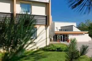 a building with trees in front of it at Hôtel du Béryl, Lons-le-Saunier in Lons-le-Saunier