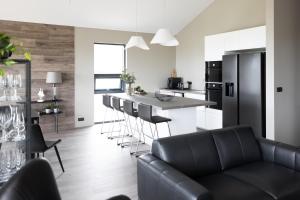 a kitchen with a couch and a bar with stools at Luxury Ocean Villas in Vestmannaeyjar