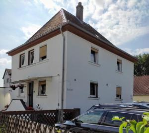 een wit huis met een auto ervoor geparkeerd bij Gästezimmer Boxenstopp in Veitsbronn