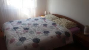 a bed with a floral comforter on it in a bedroom at Apartmani Stojan in Povljana