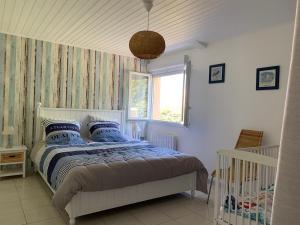 ein Schlafzimmer mit einem Bett mit blauen Kissen und einem Fenster in der Unterkunft les mouettes in LʼÎle-dʼOlonne