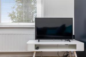 a flat screen tv sitting on top of a white stand at Hazelgrove Serviced Apartment by Huluki Sussex Stays in Haywards Heath