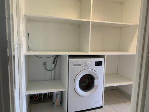 eine Waschküche mit Waschmaschine und Regalen in der Unterkunft les mouettes in LʼÎle-dʼOlonne